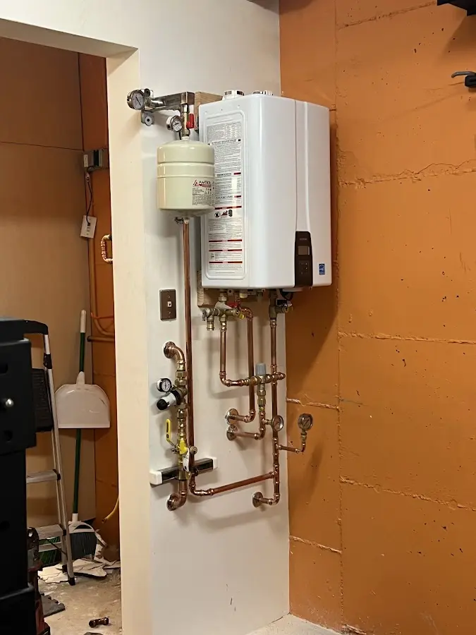 Plumbing technician inspecting water heater connections in Rineyville
